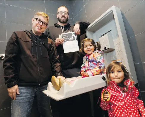  ?? CRAIG GLOVER / POSTMEDIA NEWS ?? Brett Roberts, left, and Jeremy McCall, with Roberts’ daughters Abby, 2, and Miya, 3, show the new baby changing table in the men’s washroom at Dolcetto restaurant in London, Ont., on Thursday. The men are members of Dad Club, which is asking other establishm­ents to follow suit.