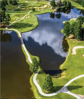  ?? HYOSUB SHIN / HYOSUB.SHIN@AJC.COM ?? An aerial view of the Heritage course at Tucker’s Heritage Golf Links shows the par-4 ninth hole’s 442-yard challenge: The tee shot must clear the water to reach the fairway, but then more water awaits to taunt the golfer on the right side all the way to the green.