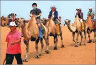  ?? GE JUN / FOR CHINA DAILY ?? Tourists ride camels in the Kubuqi Desert.