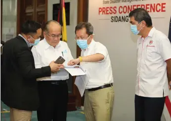  ?? Photo by Chimon Upon ?? Uggah (second left) goes through his notes with Local Government and Housing Minister Dato Sri Dr Sim Kui Hian (second right) and Major Ismail Mahidin (left) from the SDMC secretaria­t prior to the start of the press conference. Looking on is Sarawak Health director Dr Chin Zin Hing. —