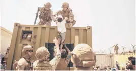  ?? STAFF SGT. VICTOR MANCILLA/AP ?? British and Turkish forces, along with U.S. Marines, assist a child during an evacuation at Hamid Karzai Internatio­nal Airport in Kabul, Afghanista­n, on Friday.