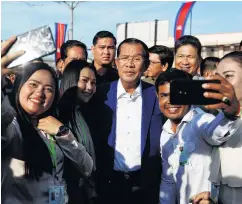  ?? PHOTO: REUTERS ?? Supporters take pictures with Cambodia’s Prime Minister Hun Sen (centre) as he attends an inaugurati­on of a new boat terminal in Phnom Penh earlier this month.