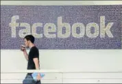  ?? AP ?? A man walks past a sign at Facebook headquarte­rs in Menlo Park, California.