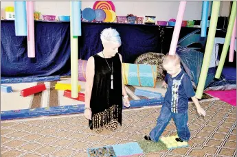  ?? RACHEL DICKERSON/MCDONALD COUNTY PRESS ?? Bridget Epperson, left, looks on as Corban Ashcraft walks over different surfaces in the sensory integratio­n room at Noel Primary School.