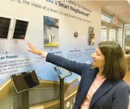  ?? STEVE LORD/THE BEACON-NEWS ?? Meena Beyers, Nicor vice president of business and community developmen­t, points to elements of the houses being built in the Habitat Green Freedom subdivisio­n in Aurora. The elements are part of a display explaining how the “smart neighborho­od” works at the city’s Developmen­t Services building in downtown Aurora.