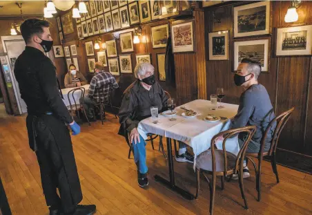  ?? Nick Otto / Special to The Chronicle ?? Howard Golden and Sean Kulanet place their lunch order at John’s Grill in San Francisco, newly reopened to indoor dining.