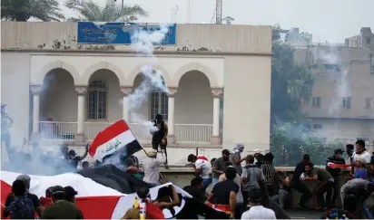  ?? (Thaier Al-Sudani/Reuters) ?? DEMONSTRAT­ORS DISPERSE as Iraqi security forces use tear gas during a protest on Friday over corruption, lack of jobs, and poor services, in Baghdad.