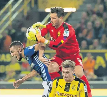  ?? FOTO: IMAGO ?? Dreikampf im Derby: Borussia Dortmunds Torwart Roman Bürki greift sich den Ball vor dem Schalker Nabil Bentaleb. Lukasz Piszczek schaut lieber gar nicht hin.