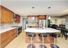  ??  ?? The kitchen in the Ferguson Road home in Tsawwassen boasts a five-burner stove, maple-style cabinets and a large island with breakfast bar.