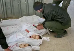  ?? AFP ?? A Syrian mourns next to bodies of children killed during air strikes in Arbin. —