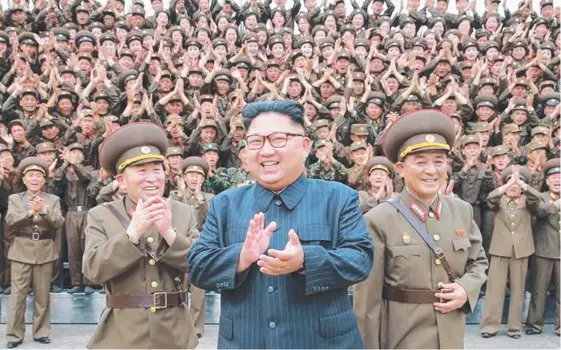  ?? Picture: KCNA ?? Kim Jong-un poses with officers and troops outside the KPA Strategic Force HQ after being ‘briefed’ (below) on plans to launch missiles towards Guam.