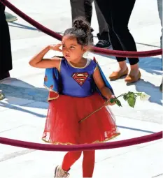  ?? ALEX BRANDON/USA TODAY NETWORK ?? A child in a Supergirl costume pays her respects to Ginsburg, who was a pop culture icon and a hero to many women and girls. The associate justice inspired books and movies, jewelry and apparel, and even Halloween costumes.