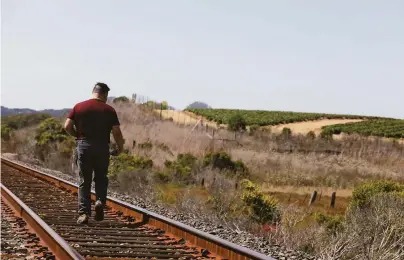  ?? Lea Suzuki / The Chronicle ?? Author Jaime Cortez walks along the railroad tracks at Kirby Park amid fields of strawberri­es in Watsonvill­e.