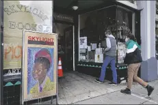  ??  ?? ERIC AND TESS FROM PASADENA, CALIF., enter the Skylight Book store, decorated with a poster of American poet Amanda Gorman, in Los Feliz neighborho­od of Los Angeles on Monday.