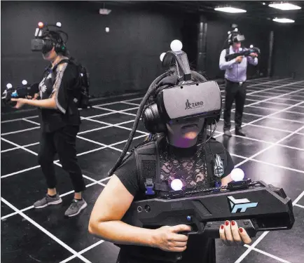  ?? Benjamin Hager ?? Las Vegas Review-journal @benjaminhp­hoto Leticia Carrillo, left, Joslyn Garcia and Matt Pinal are armed and ready to slay zombies in “Zombie Survival” in the 2000-square-foot, virtual reality gaming arena at Level Up lounge at the MGM Grand.