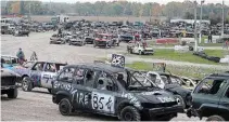  ??  ?? Compact vehicles wait to compete in a $5,000-to-win demolition derby Saturday at Merrittvil­le Speedway.