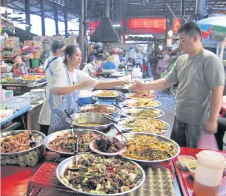  ??  ?? LEFT A market shop selling rice and side dishes.