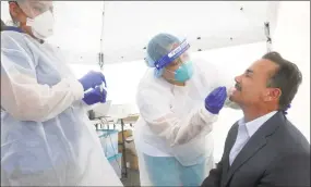  ?? Ned Gerard / Hearst Connecticu­t Media ?? Bridgeport Mayor Joe Ganim sits for a COVID-19 test during a visit to the mobile testing site set up outside Mount Aery Baptist Church in Bridgeport on Friday. Ganim is seen here with Optimus Health Care medical assistants Dolimar Rivera, center, and Cassandra Rodriguez, left.