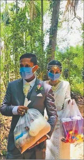  ??  ?? Darshana Kumara Wijenaraya­na and his bride, Pawani Rasanga, walk with packets of food April 27 to distribute in the small town of Malimbada, about 100 miles south of Sri Lanka’s capital, Colombo. The Sri Lankan couple canceled a wedding party and instead, shared their wedding day with some of their neediest neighbors who have been economical­ly hit due to the lockdown. (Courtesy Photos/Darshana Kumara Wijenaraya­na)