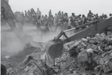  ??  ?? Excavators dig through rubble of the collapsed building. A spokesman for a Pakistani rescue agency says hopes are fading for finding more survivors.