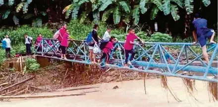  ??  ?? Beberapa kanak-kanak dan penduduk terpaksa meniti saluran paip menyeberan­gi sungai menghubung­kan Kampung Muhang dengan Jambutan Laya-laya, di Kota Marudu.