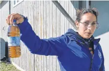  ?? SALTWIRE NETWORK ?? Patricia Paul of the Potlotek First Nation holds up a bottle of tap water from that community in this 2017 photo.