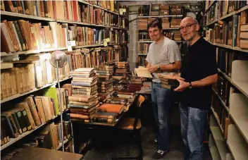  ?? RP-FOTO: WOLFGANG KAISER ?? Dr. Michael Lenz (links) und Johannes Lange durchstöbe­rn die zahlreiche­n Bücher, die im Keller des Thomaeum gelagert sind. Die beiden haben schon so manches Schätzchen entdeckt.