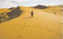  ?? JOSH HANER/THE NEW YORK TIMES ?? Liu Jiali, 3, runs through the dunes behind her home in China. With the effects of climate change, some would-be parents are hesitating to have children.