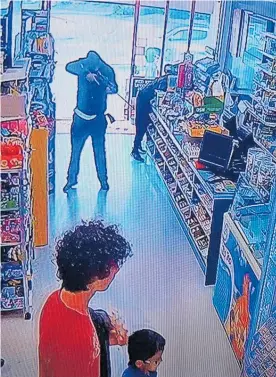  ?? Photos / Supplied ?? Children can be seen in the store while the offender points a gun down the aisle of the Waipapa Superette during the Saturday afternoon robbery.