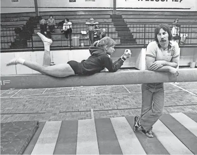  ??  ?? Gymnist Lucy Wener takes a break on the balance beam and relaxes with coach David Neel on March 19, 1981. BARNEY SELLERS / THE COMMERCIAL APPEAL