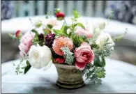  ??  ?? A Cathy Graham arrangemen­t includes dahlias, garden roses and ranunculus plus fragrant rosemary, which signifies remembranc­e. It would make a nice Mother’s Day or get-well arrangemen­t. (Quentin Bacon)