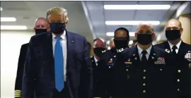  ?? PATRICK SEMANSKY — THE ASSOCIATED PRESS ?? President Donald Trump wears a face mask as he walks down a hallway during a visit to Walter Reed National Military Medical Center in Bethesda, Md., on Saturday.