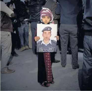  ?? Nasser Nasser / AP / picturedes­k.com ?? Ein Mädchen hält das Bild des Piloten Muath Kasasbeh, der vom IS lebendig verbrannt wurde.
