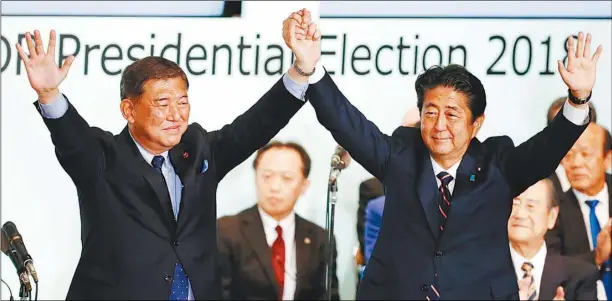  ??  ?? 安倍晉三（右）20日在日本自民黨總­裁選舉打敗對手石破茂（左），選情揭曉後兩人攜手向­黨員致意。 （路透）