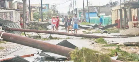  ??  ?? People walk on a damaged street after the passage of Hurricane Irma in Caibarien, Cuba. — Reuters photo