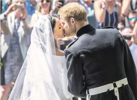  ??  ?? PERFECT DAY: The newly married Duke and Duchess of Sussex kiss to the huge delight of the crowds at Windsor