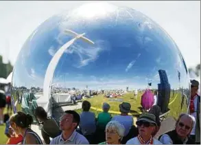  ??  ?? Gäste suchen in Wittenberg auf der Festwiese Schatten hinter einem großen silbernen Ball, der für den Festgottes­dienst genutzt wurde. Foto: Maurizio Gambarini, dpa