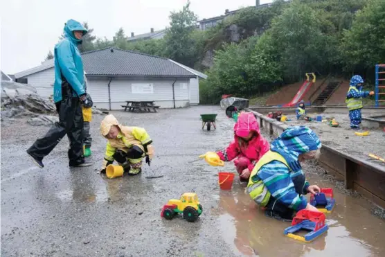  ??  ?? UTELEK: Matheo Vang Butz (3), Norah Marie Gullmark (5) og Hans Eivind Hesvik (5) i Skogsvåg Barnehage i Sund syns det er helt greit å leke ute selv om det bøtter ned. Fagarbeide­r Gunn Berit Hummelsund passer på.