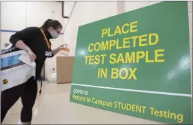  ?? COURTESY OF PENN STATE HEALTH ?? Hannah Bennett, a graduate assistant at Penn State College of Medicine in Hershey, drops off her sample during COVID-19 testing for students returning to campus in early December.