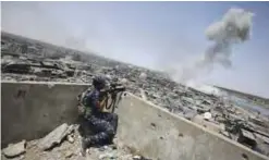  ?? — AFP ?? An Iraqi forces sniper looks on as smoke billows following an airstrike by US-led internatio­nal coalition forces targeting Islamic State in the Old City of Mosul yesterday.