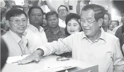  ??  ?? WORLD’S LONGEST SERVING LEADER — Cambodian Prime Minister Hun Sen, center, of the Cambodian People’s Party touches a ballot box after casting his ballot at a polling station in Takhmua in Kandal province, southeast of Phnom Penh, Cambodia, Sunday, July...