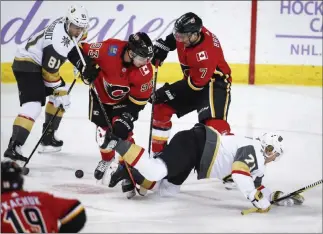  ?? Jeff Mcintosh ?? The Associated Press Knights center William Karlsson, right, hits the ice as teammate Jonathan Marchessau­lt, left, and Calgary’s Sam Bennett, center, and T.J. Brodie all scramble for a loose puck in Monday’s game.