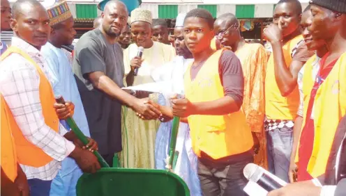  ?? Photo Abubakar Sadiq Isah ?? Chairman of Wuse Market Traders Associatio­n, Mr. Okorie Raphel Ikechukwu (3rd left), presents a wheel barrow to one of the benefiacia­ries of a cooperativ­e soft loan scheme provided by the associatio­n at the market, recently