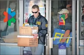  ?? Scott Olson Getty Images ?? FEDERAL AGENTS carry evidence from a FedEx store in Sunset Valley, Texas, from which authoritie­s believe two package bombs were mailed.