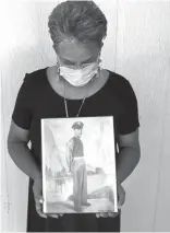  ?? Gerald Herbert/Associated Press, File ?? ■ Belvin Jefferson White poses with a portrait of her father, Saymon Jefferson, on May 18 at Jefferson’s home in Baton Rouge, La. White recently lost both her father and her uncle, Willie Lee Jefferson, to COVID-19.