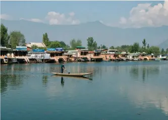  ?? — AFP ?? A local man rows a boat near houseboats hotels in Dal Lake in Srinagar.