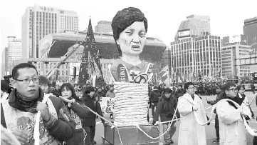  ??  ?? Protesters carry an effigy of Park during an anti-government rally demanding the resignatio­n of the president in central Seoul. — AFP photo