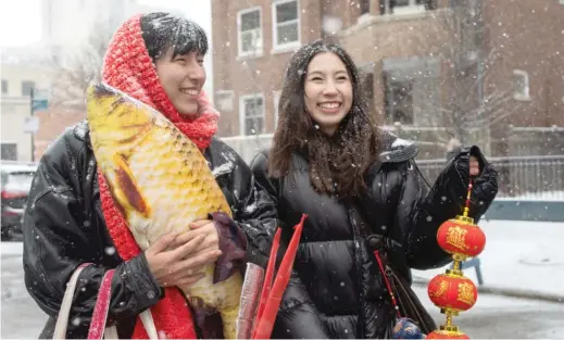  ?? ?? Lily Lee, 20, holds a stuffed fish while her sister Lidia Lee, 14, holds a string of lanterns during the Lunar New Year Parade in the Uptown neighborho­od.