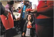  ?? Guillermo Arias / AFP / Getty Images ?? Migrants trying to reach the U.S. border, most of them Hondurans, eat at a shelter in Puebla, Mexico.