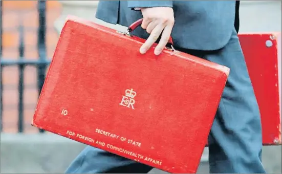  ?? TOLGA AKMEN / AFP ?? Un miembro de seguridad se lleva las dos carteras rojas del ministro de Exteriores, Boris Johnson, tras su dimisión